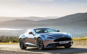 日落時分，銀色Aston Martin跑車停在風景優美的山路上。 — MacBook Pro 13 壁紙