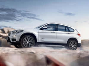 銀色BMW X1 SUV在沙漠中快速行駛，揚起灰塵。 — 奧迪 GIF 壁紙