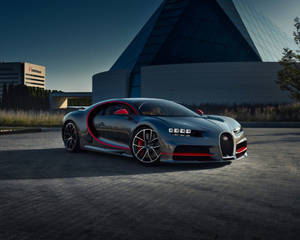 銀色Bugatti Chiron帶紅色飾邊，黃昏時停泊在玻璃金字塔建築前。 — 汽車 壁紙