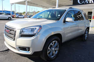 銀色GMC Acadia SUV在明亮的陽光下停放在汽車經銷商場地。 — Surface Pro 壁紙