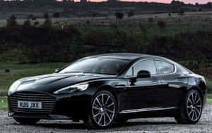 黑色Aston Martin停在碎石上，背景有山丘和日落 — Steam Deck OLED 壁紙