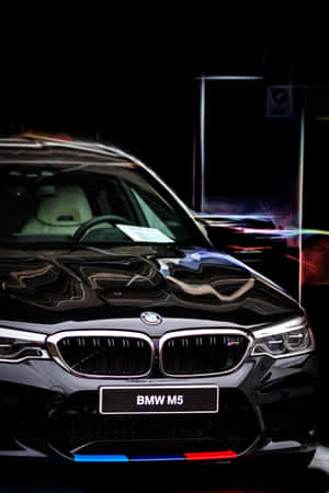 黑色BMW M5跑車，霓虹燈在其閃亮表面上反射。 — 汽車 壁紙