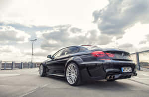 黑色BMW M6跑車停泊在陰天，配銀色輪圈。 — MacBook Pro 16 壁紙