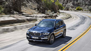 黑色BMW X3 SUV在岩石地形的彎曲沙漠公路上快速行駛。 — 平治 C300 壁紙