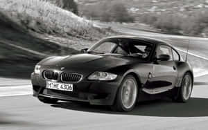 黑色BMW Z4在彎曲的道路上加速，周圍環境模糊。 — Steam Deck 壁紙