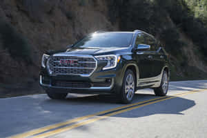黑色GMC Acadia SUV在山路上行駛，帶有模糊動態效果。 — Surface Laptop 壁紙