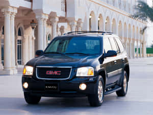 黑色GMC Envoy SUV停在一座白色柱廊建築前。 — 4:3 壁紙