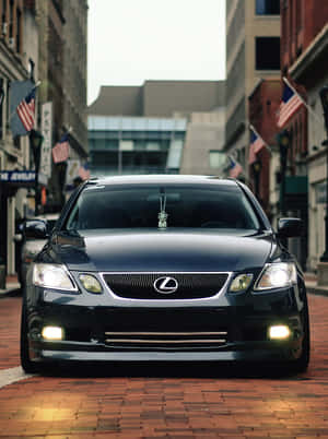 黑色Lexus轎車停在磚砌街道上，建築物上掛有美國國旗。 — HMD Terra M 壁紙