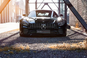 黑色Mercedes-AMG GT停在工業鋼拱門下，金色夕陽。 — 汽車 壁紙