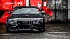 黑色奧迪RS5跑車停在潮濕的路面上，靠近紅色塗鴉牆。 — Audi R8 GIF 壁紙