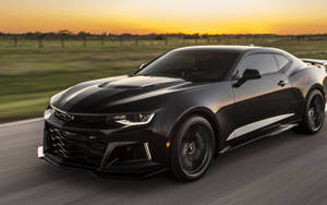 黑色雪佛蘭Camaro ZL1在金色日落時分在鄉村道路上飛馳。 — 黑色動態圖 壁紙