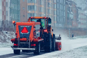 橙色剷雪車在冬季清理城市街道上的積雪。 — MacBook Air 13 壁紙