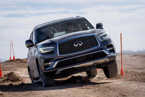 深灰色 Infiniti SUV 在設有橙色雪糕筒的泥土障礙賽道上行駛。 — Surface Pro 壁紙