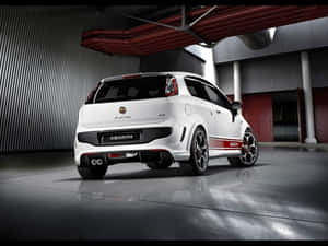 白色 Abarth Punto EVO 跑車在工業車庫內，帶紅色點綴和拋光地板。 — 酷車 壁紙