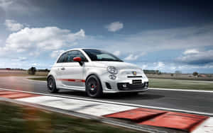 白色 Fiat Abarth 賽車在賽道上疾馳，帶有動態模糊效果。 — MacBook Pro 13 壁紙