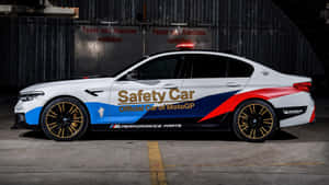 BMW M5 MotoGP安全車在工業車庫內，帶有德文標誌。 — 酷車 壁紙