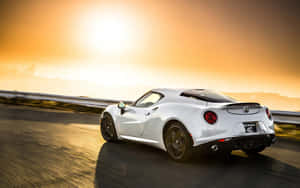 白色Alfa Romeo 4C在金色日落的海岸公路上飛馳。 — Steam Deck 壁紙
