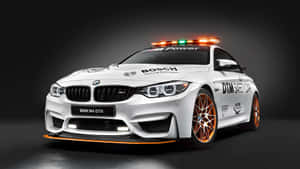 白色BMW M4 GTS安全車，帶有橙色飾邊和閃爍燈光，在工作室中。 — Studio Display 壁紙