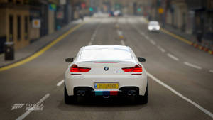 白色BMW M6跑車在黃昏時分行駛在城市街道上。 — 白色 壁紙