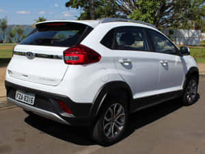 白色Chery Tiggo 3x SUV停泊在靠近水和樹木的陽光明媚街道上。 — 酷車 壁紙