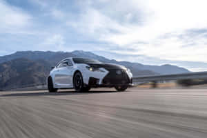白色Lexus跑車在雪山道路上飛馳。 — Surface Laptop 壁紙
