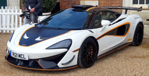 白色和橙色的McLaren Senna超級跑車停在磚砌建築附近的礫石上。 — 4K 法拉利 壁紙