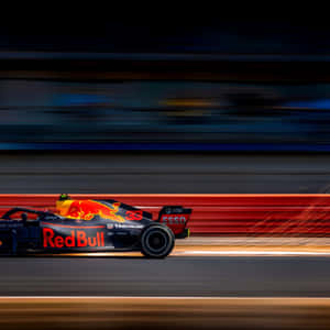 紅牛F1賽車在日落時分的賽道上以動態模糊高速行駛。 — iPad 第10代 壁紙