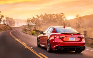 紅色 Alfa Romeo 房車在夕陽下行駛在蜿蜒的道路上。 — Steam Deck OLED 壁紙