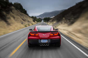 紅色Corvette在山路上疾馳，帶有動態模糊效果。 — Surface Pro 壁紙
