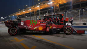 紅色法拉利F1賽車55號夜間停泊在維修區通道，附近有車隊成員。