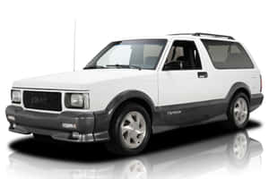 白色GMC Typhoon SUV，帶有黑色飾邊和銀色輪圈，在反射的攝影棚地板上。 — Surface Laptop 壁紙