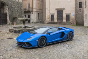 藍色林寶堅尼 Aventador 在鵝卵石街道上，靠近石噴泉和舊建築。 — 汽車 壁紙