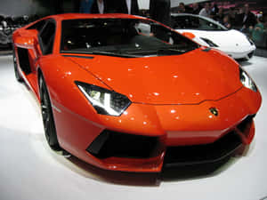 橙色林寶堅尼Aventador在車展上展出，後面有群眾。 — 蘭博基尼 壁紙
