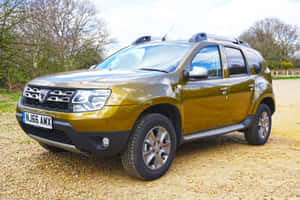 金色Dacia Duster SUV停泊在碎石上，靠近樹木 — MacBook Pro M2 壁紙