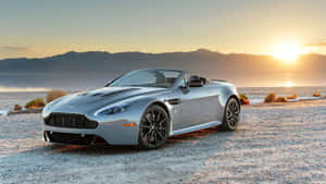 銀色 Aston Martin 開篷車停在金色日落時分的沙漠碎石上。