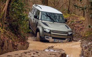 銀色 Land Rover Defender 在泥濘森林溝渠中行駛。 — MacBook Pro 13 壁紙