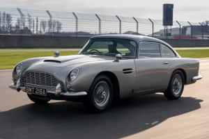 銀色Aston Martin DB5在賽道上疾馳，司機可見。 — Surface Laptop 壁紙