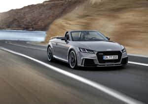 銀色Audi TT Roadster在海洋和懸崖的海岸公路上快速行駛。 — 奧迪 GIF 壁紙