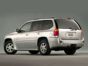 銀色GMC Envoy SUV從後方四分之三角度拍攝的攝影棚照片。 — 低飽和度 壁紙