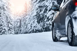 銀色汽車停在積雪道路上，周圍是冬日陽光下雪覆蓋的松樹。 — MacBook Pro M4 壁紙