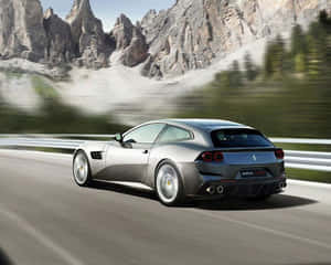 銀色法拉利 GTC4Lusso 在山路上疾馳，背景有岩石山峰和模糊的樹木。 — 4K 法拉利 壁紙