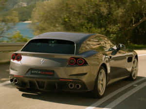銀色法拉利 GTC4Lusso 在日落時分行駛在風景如畫的海岸公路上。 — 4K 法拉利 壁紙