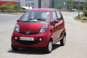 紅色 Tata Nano 汽車停在鋪砌道路旁，靠近建築物。 — 3:2 壁紙