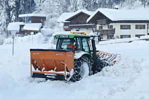 除雪拖拉機在冬天清理村莊街道上的積雪。 — MacBook 壁紙