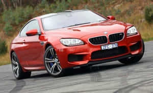紅色BMW M6跑車喺蜿蜒嘅道路上行駛，周圍係綠色植物。 — Steam Deck 壁紙