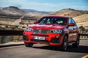 紅色BMW X4 M40i在沙漠高速公路上行駛，背景有山丘。 — MacBook Air 13 壁紙