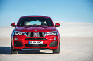 紅色BMW X4 M在明亮陽光下停泊在沙漠景觀中。 — MacBook Pro 16 壁紙