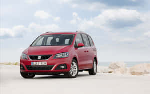 紅色SEAT Alhambra小型貨車停泊在多雲天空下的海岸岩石附近。 — MacBook Pro 13 壁紙