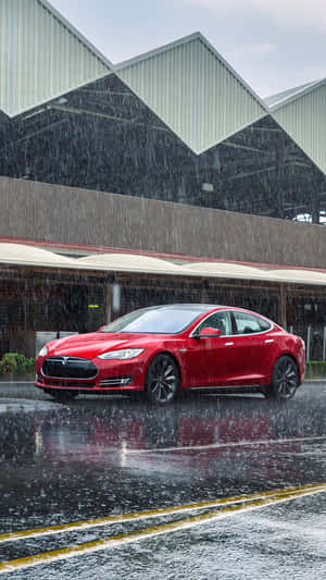 紅色Tesla汽車在雨中停在濕漉漉的城市街道上，靠近工業建築。 — Tesla GIF 壁紙