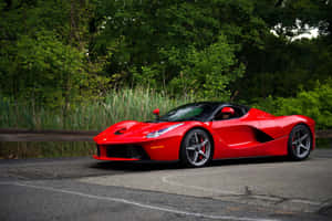 紅色法拉利 LaFerrari 停泊在綠葉成蔭的森林道路上。 — MacBook Air 13 壁紙